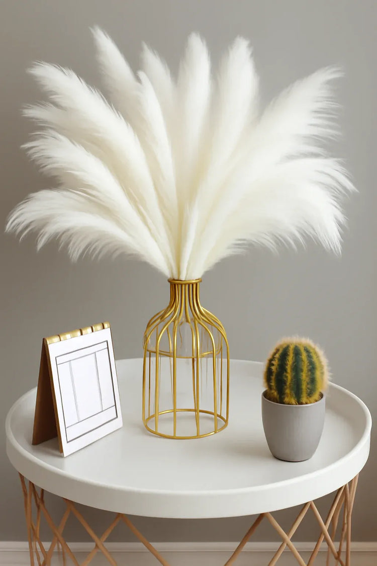 Decorative arrangement with white feathers in a gold vase on a round table.