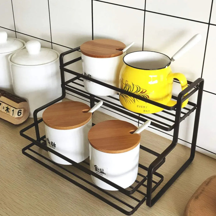 Kitchen storage rack with white containers, a yellow mug, and wooden lids on a tiled floor.