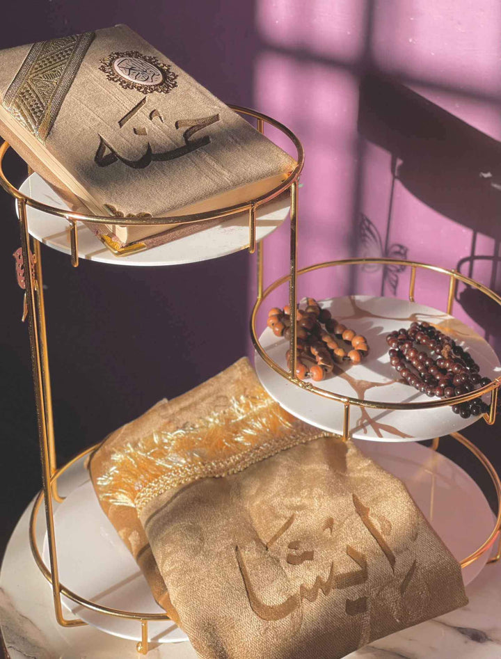 Gold and white decorative stand with towels and a book on a purple background