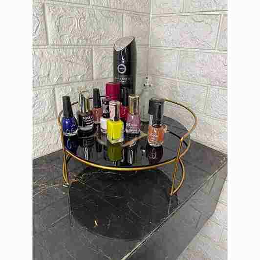 Round black marble tray with gold rim holding various nail polish bottles on a tiled bathroom floor.