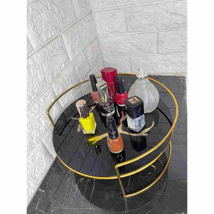 Round black table with gold frame holding various nail polish bottles on a tiled floor.
