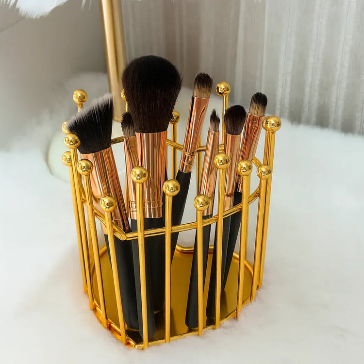 Set of makeup brushes in a gold holder on a white background
