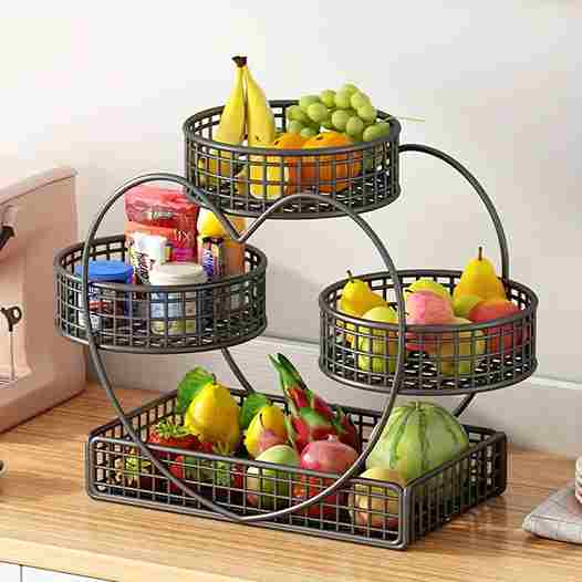 Three-tiered metal fruit basket with various fruits on a wooden surface.