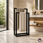 Bathroom scene with a towel rack holding a beige towel, next to a sink with toiletries and a plant.
