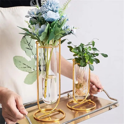 Two gold and glass vases with plants on a tray