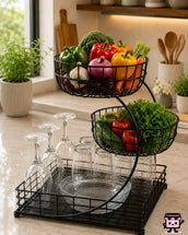 Two-tiered metal basket with fruits, vegetables, and glasses in a kitchen setting