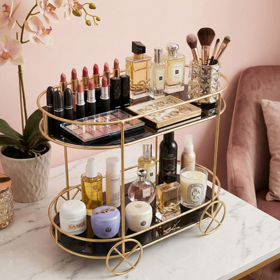 Gold makeup cart with various cosmetic products on a marble surface.
