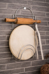 Wooden rolling pin and round object on a metal stand against a tiled wall.